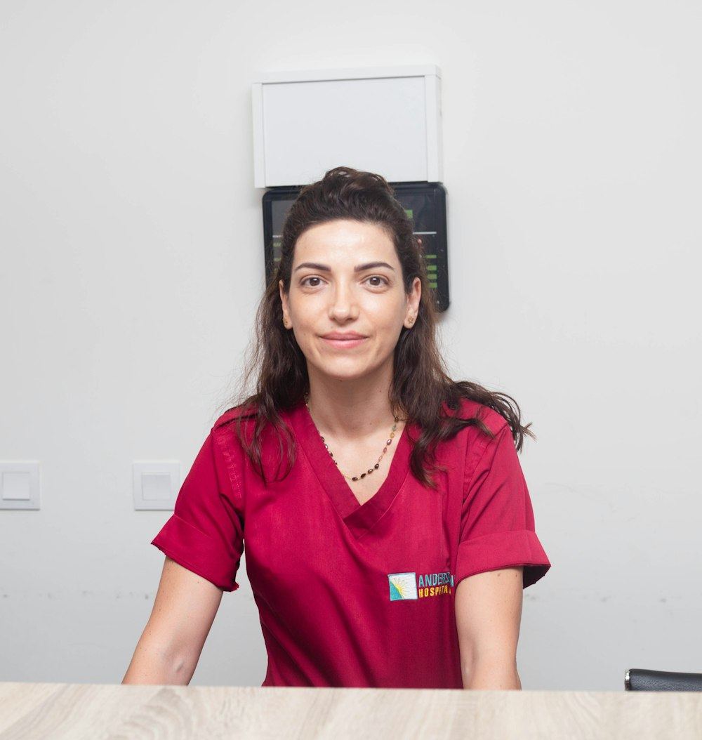 A hospital team member in red scrubs smiling at the front desk